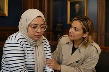 Parkta bir bankta oturan genç bir kadın konuşurken arkadaşı elini onun koluna koyarak güven verici bir şekilde dinliyor